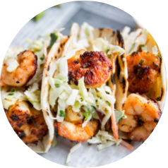 Grilled shrimp tacos topped with shredded cabbage and cilantro in soft tortilla shells.