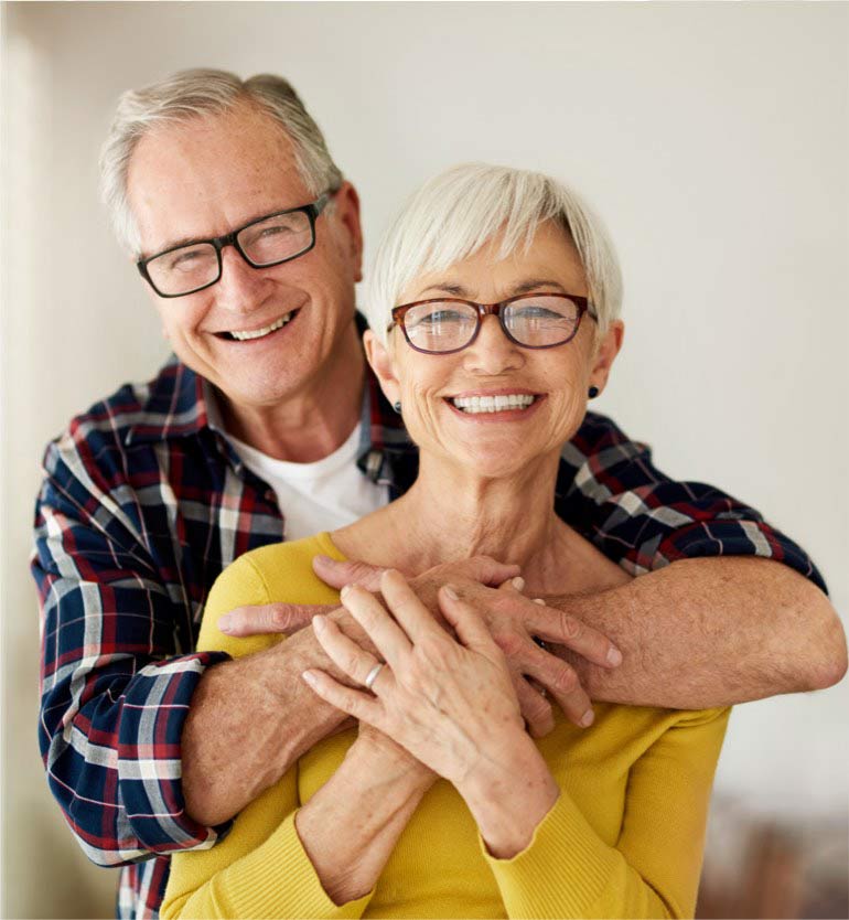 senior-couple Happy senior couple smiling joyfully while embracing each other indoors