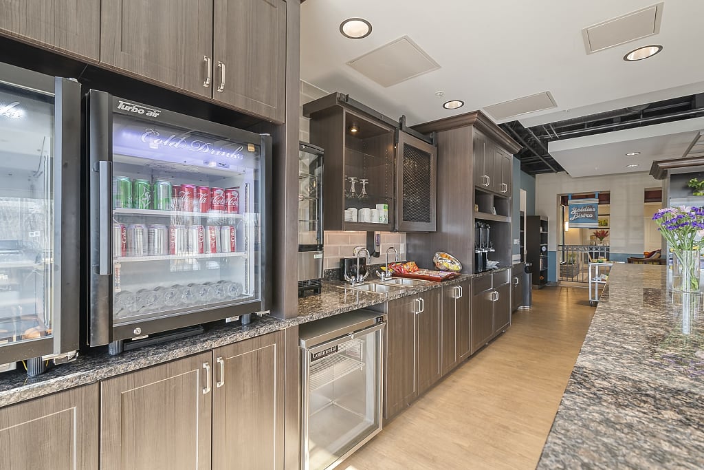 Kitchen with modern dark wood cabinets and modern mini fridges stocked with soda cans.