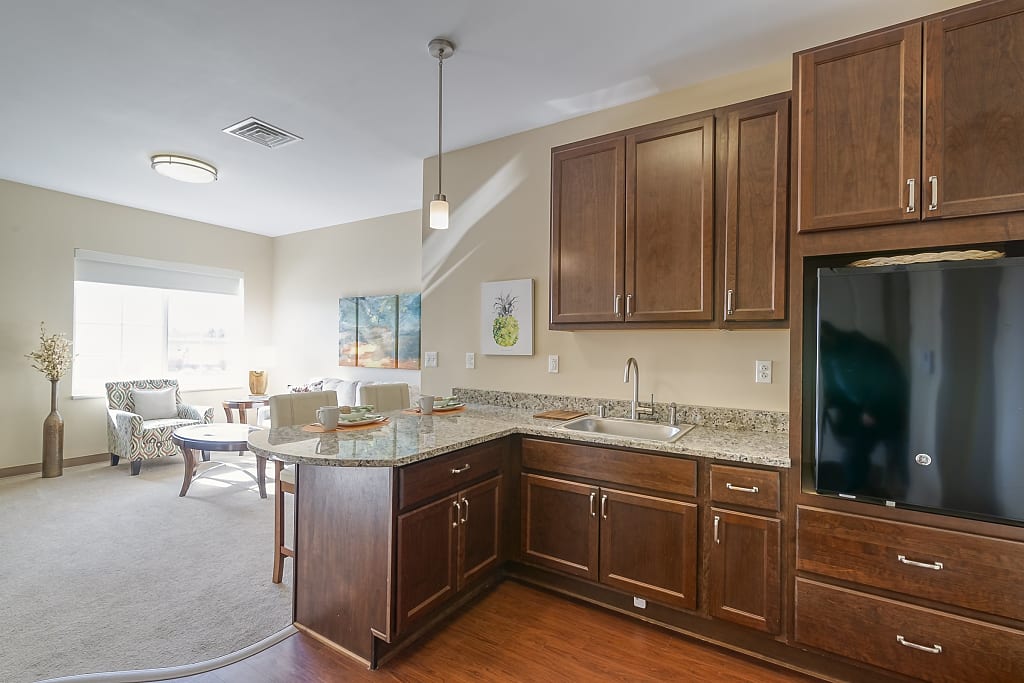Clean kitchen with a mini fridge looking into a bright living area.