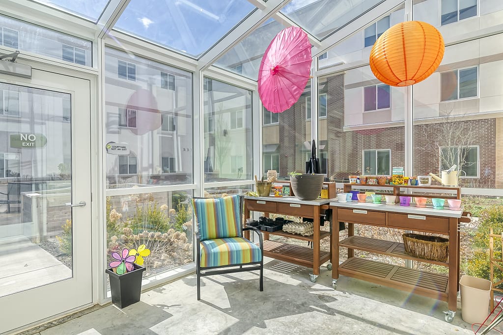 Bright sunroom with gardening supplies and a seat.