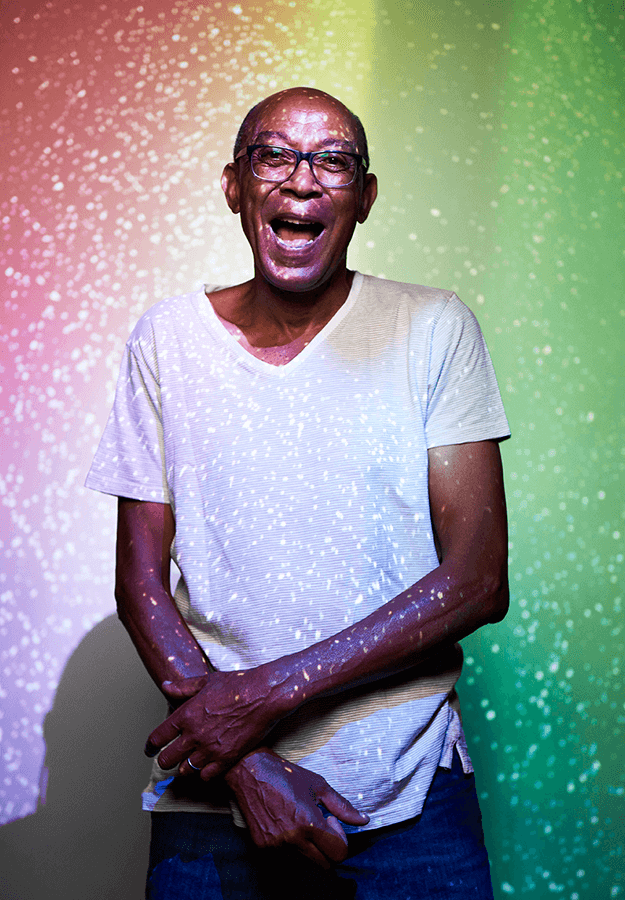 avalon-commerce-township-rainbow-projection-on-man Senior man stands in projection light and laughs