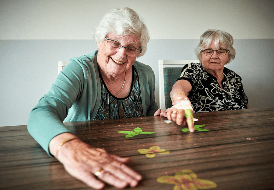 avalon-commerce-township-women-using-magic-table Two elderly women using the magic table at the Avalon of Commerce Township