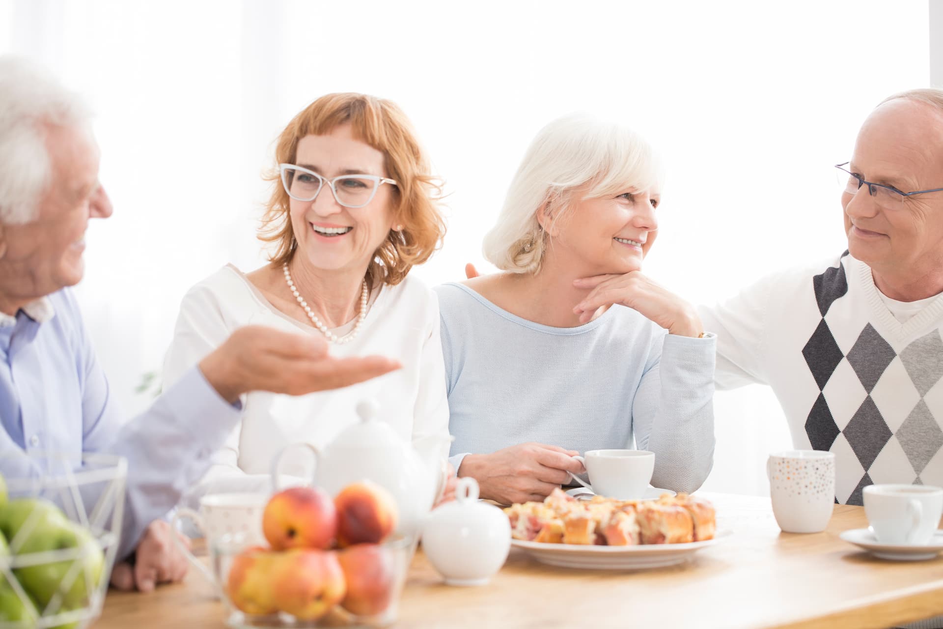 senior friends having a conversation over coffee and tea