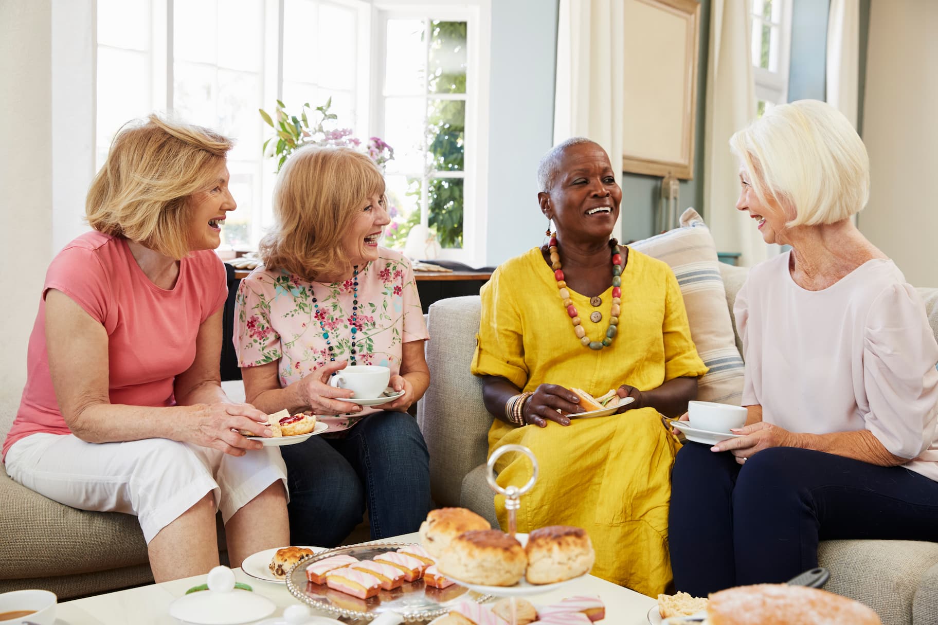 group of senior women chatting and laughing on couch