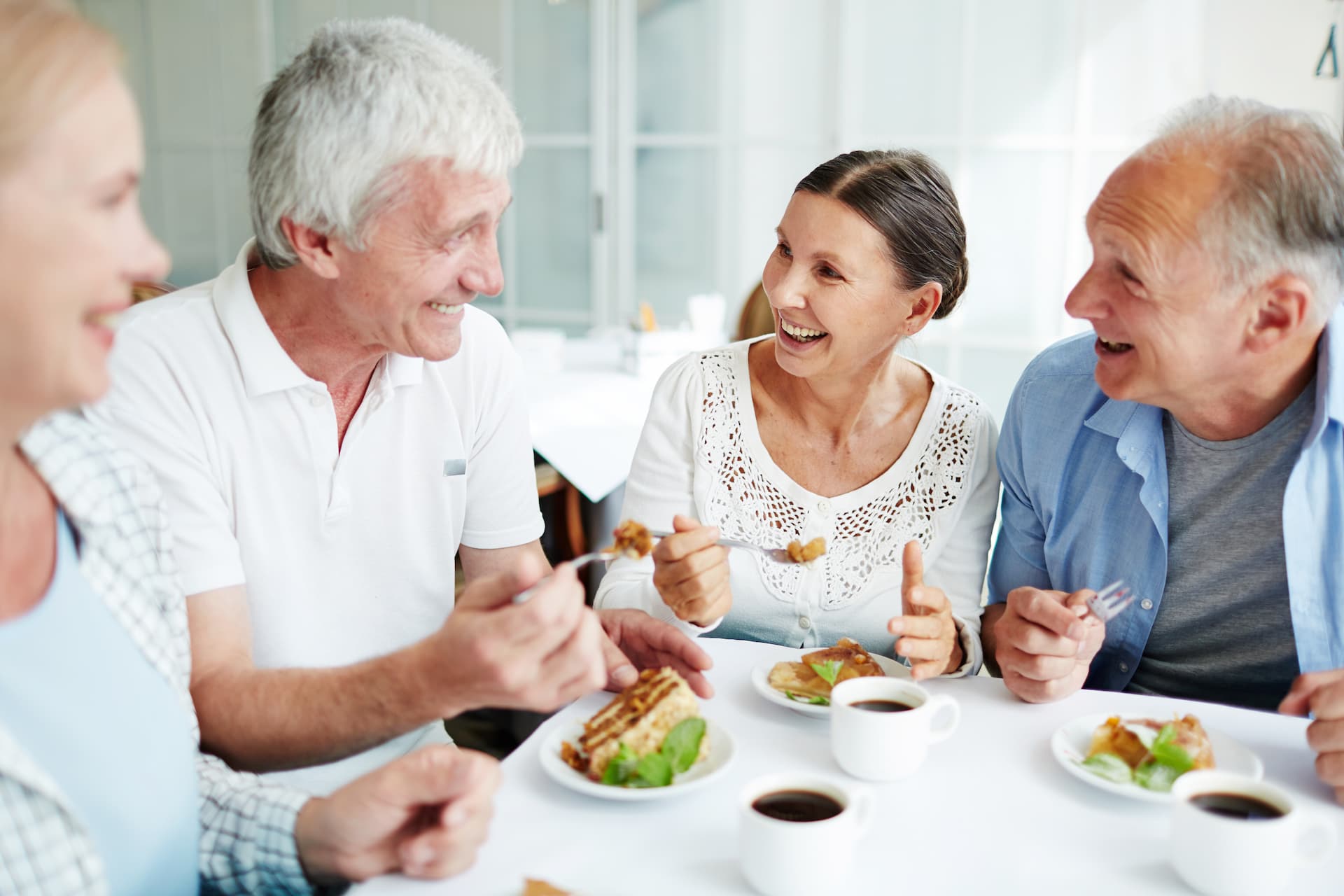 senior friends laughing around table at breakfast